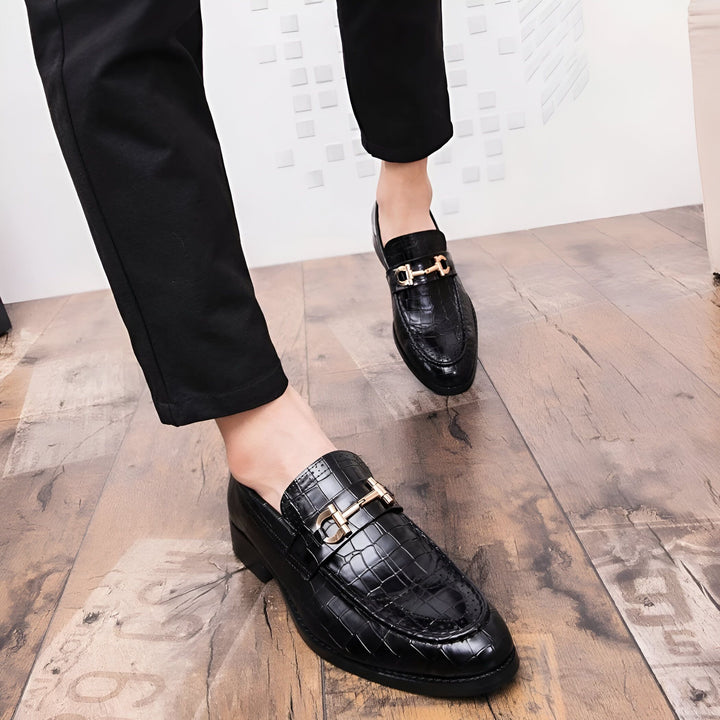 Gros plan de mocassins noirs en cuir crocodile avec boucle dorée, portés avec un pantalon noir élégant sur un parquet clair. Chaussures de luxe pour hommes, style formel et sophistiqué., 45286694322357,45286694355125,45286694387893,45286694420661,45286694453429,45286694486197,45286694518965,45286694551733,45286694584501,45286694617269,45286694650037,45286694682805,45286694715573,45286694748341,45286694781109,45286694813877,45286694846645,45286694879413,45286694912181,45286694944949