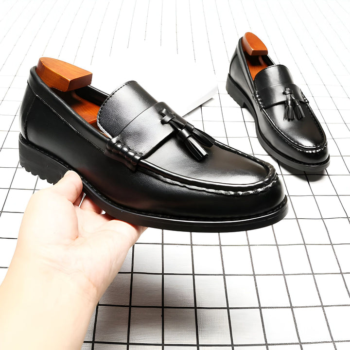 Mocassins noirs élégants avec glands, posés sur un fond à carreaux. Un embauchoir en bois est visible dans une chaussure. Style classique et raffiné., 45287074070709,45287074103477,45287074136245,45287074169013,45287074201781,45287074234549,45287074267317,45287074300085,45287074332853,45287074365621,45287074398389,45287074431157,45287074463925,45287074496693
