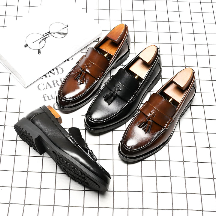 Gros plan de mocassins en cuir pour hommes, marron et noir, présentés avec des embauchoirs, sur un fond à carreaux. Une paire de lunettes et un livre sont également visibles., 45287074070709,45287074103477,45287074136245,45287074169013,45287074201781,45287074234549,45287074267317,45287074300085,45287074332853,45287074365621,45287074398389,45287074431157,45287074463925,45287074496693