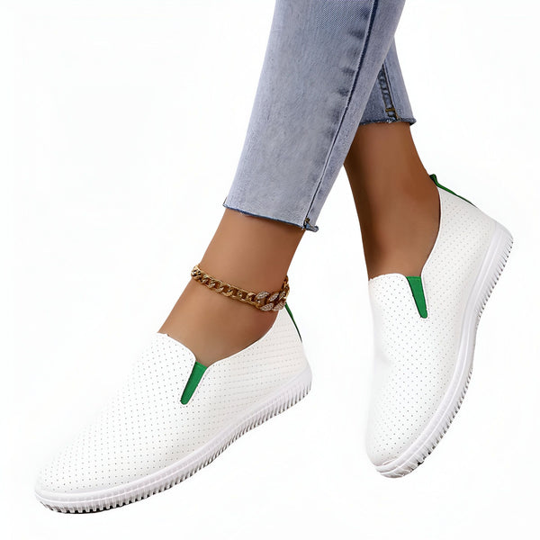 Chaussures slip-on blanches perforées avec accents verts portées par une femme avec un jean clair et une chaîne de cheville dorée., 45286923403445,45286923436213,45286923468981,45286923501749,45286923534517,45286923567285