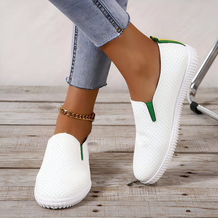 Chaussures blanches perforées portées avec un jean et une chaîne de cheville dorée, parfaites pour un look décontracté et tendance. Style slip-on avec détails verts et jaunes., 45286923403445,45286923436213,45286923468981,45286923501749,45286923534517,45286923567285