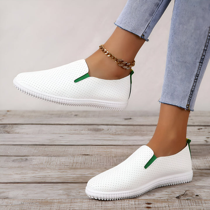 Chaussures décontractées blanches à enfiler avec détails verts, portées avec une chaîne de cheville dorée et un jean, sur un plancher en bois., 45286923403445,45286923436213,45286923468981,45286923501749,45286923534517,45286923567285