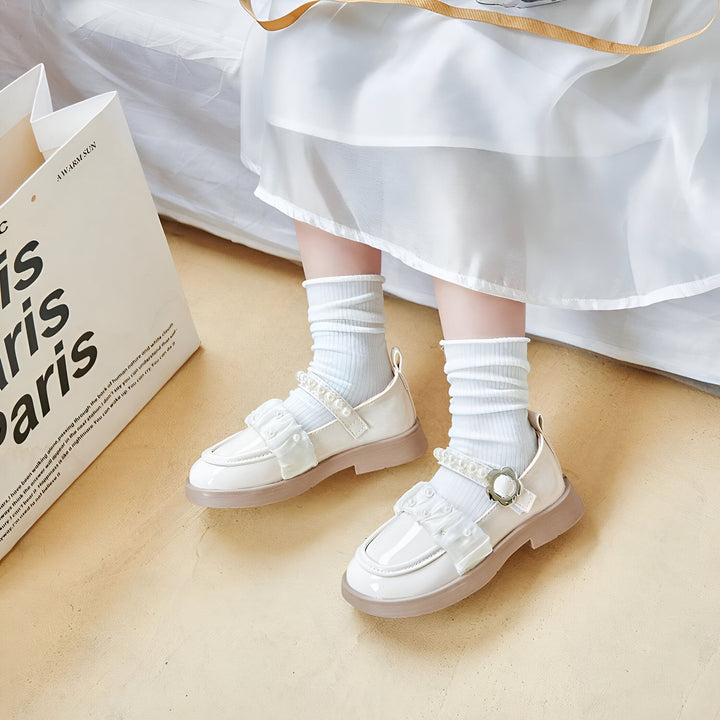 Vue rapprochée des pieds d'une jeune fille portant des chaussures blanches vernies avec des détails en dentelle et des chaussettes blanches. Un sac de shopping avec l'inscription "Paris" est visible en arrière-plan., 45287012860085,45287012892853,45287012925621,45287012958389,45287012991157,45287013023925,45287013056693,45287013089461,45287013122229,45287013154997,45287013187765,45287013220533,45287013253301,45287013286069,45287013318837,45287013351605,45287013384373,45287013417141,45287013449909,45287