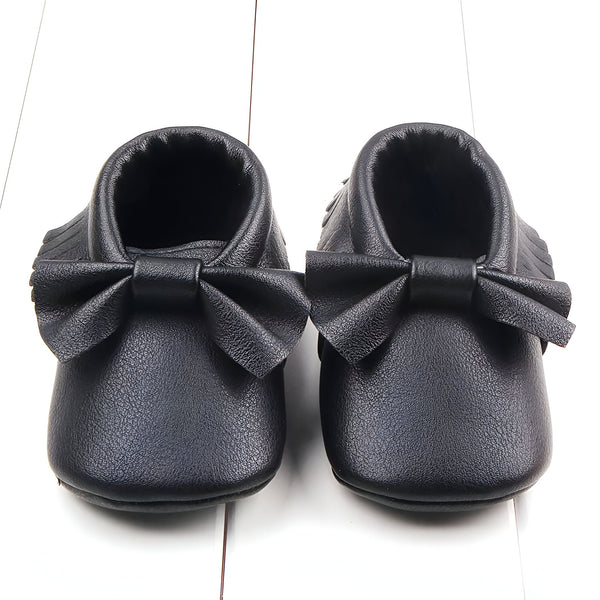 Deux chaussons de bébé noirs en cuir avec un nœud sur le devant. Les chaussures sont sur un fond blanc. Chaussures pour fille. Mocassins pour nourrissons., 45287068827829,45287068860597,45287068893365,45287068926133,45287068958901,45287068991669,45287069024437,45287069057205,45287069089973,45287069122741,45287069155509,45287069188277,45287069221045,45287069253813,45287069286581,45287069319349,45287069352117,45287069384885