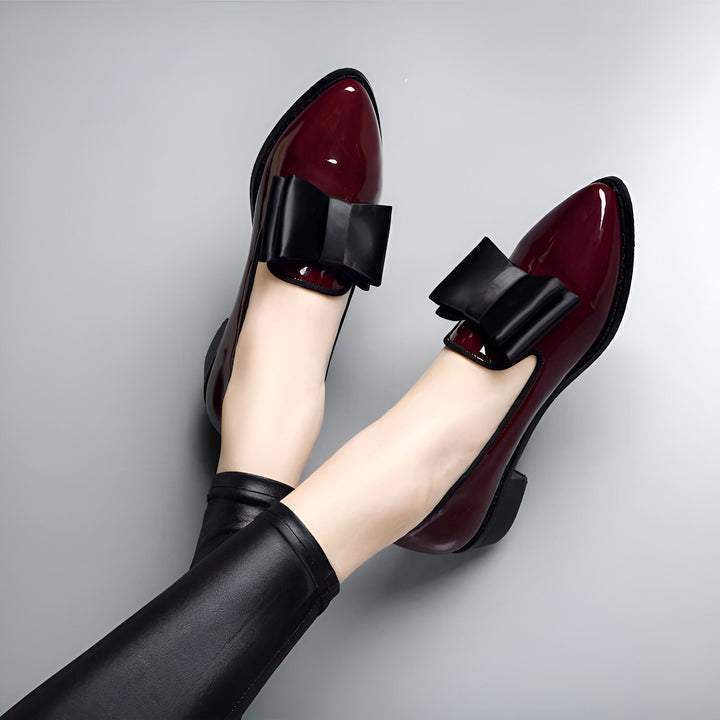 Chaussures plates bordeaux vernies avec nœud noir. Vue rapprochée des pieds chaussés avec pantalon en cuir noir. Style et élégance féminine., 45286907478197,45286907510965,45286907543733,45286907576501,45286907609269,45286907642037,45286907674805,45286907707573,45286907740341,45286907773109,45286907805877,45286907838645,45286907871413,45286907904181