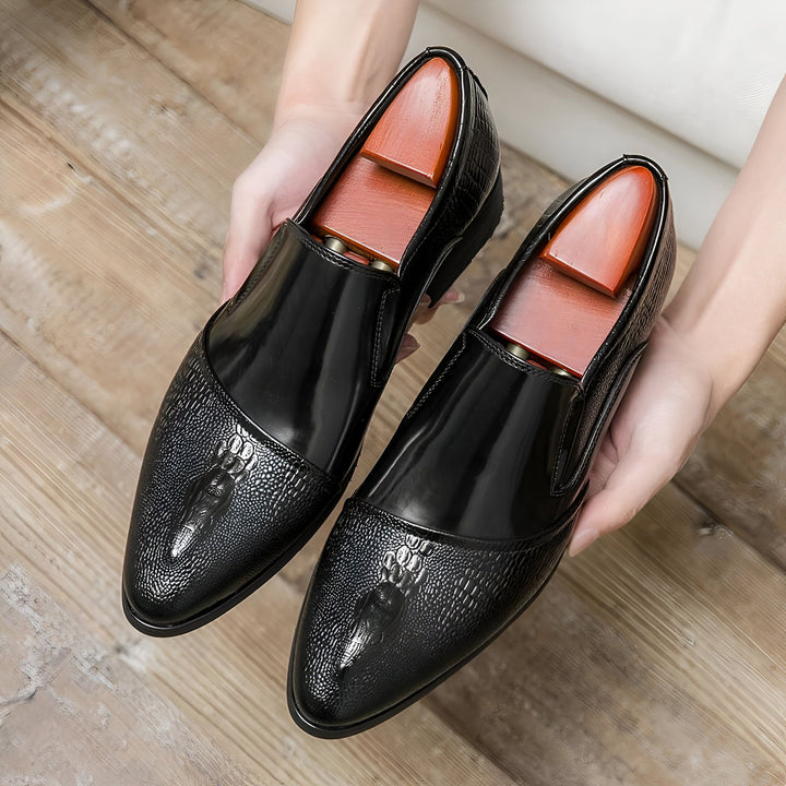 Deux chaussures en cuir noir brillantes avec des embauchoirs en bois sont tenues par des mains sur un fond en bois clair. Les chaussures présentent une partie avant texturée et une partie supérieure lisse., 45287063126197,45287063158965,45287063191733,45287063224501,45287063257269,45287063290037,45287063322805,45287063355573,45287063388341,45287063421109,45287063453877,45287063486645,45287063519413,45287063552181,45287063584949,45287063617717,45287063650485,45287063683253,45287063716021,45287063748789,