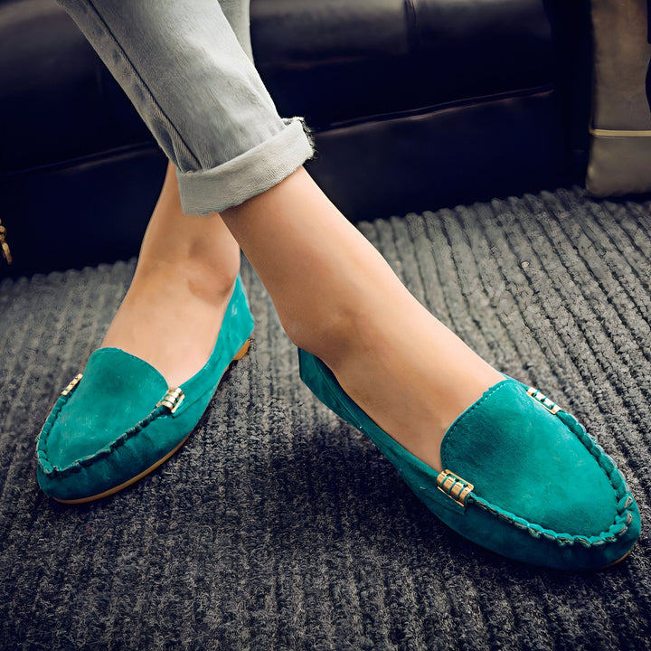 Gros plan sur une personne portant des mocassins verts en daim et un jean décontracté, assise sur un tapis gris. Les chaussures ont des détails dorés. Style décontracté et confortable., 45287116701877,45287116734645,45287116767413,45287116800181,45287116832949,45287116865717,45287116898485,45287116931253,45287116964021,45287116996789,45287117029557,45287117062325,45287117095093,45287117127861,45287117160629,45287117193397,45287117226165,45287117258933,45287117291701,45287117324469,45287117357237,452