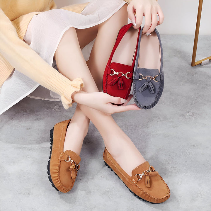 Femme assise présentant des mocassins en daim. Elle tient une paire rouge et grise. Une paire marron est à ses pieds. Chaussures à glands décontractées et élégantes. Mode femme., 45287115489461,45287115522229,45287115554997,45287115587765,45287115620533,45287115653301,45287115686069,45287115718837,45287115751605,45287115784373,45287115817141,45287115849909,45287115882677,45287115915445,45287115948213,45287115980981,45287116013749,45287116046517,45287116079285,45287116112053,45287116144821,452871161