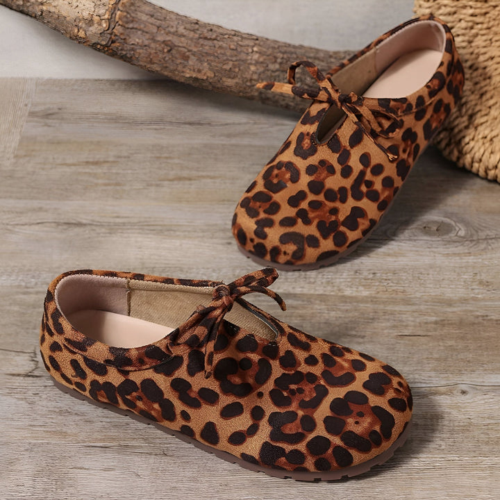 Chaussures plates à imprimé léopard avec détail de nœud, posées sur une surface en bois. Mode féminine, style animal., 45286647955637,45286647988405,45286648021173,45286648053941,45286648086709,45286648119477,45286648152245,45286648185013,45286648217781