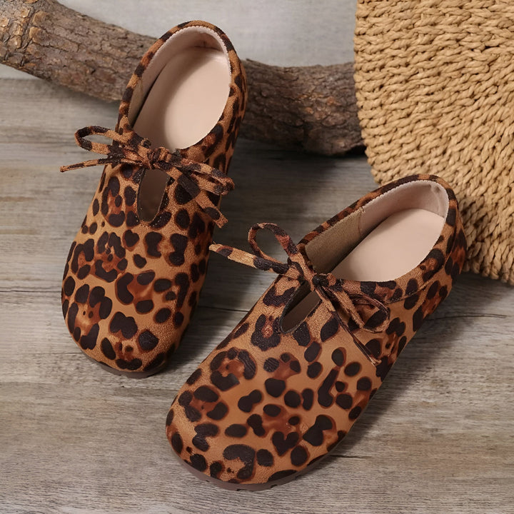 Chaussures plates pour femmes à motif léopard avec lacets noués sur un fond en bois. Sac en paille visible en arrière-plan., 45286647955637,45286647988405,45286648021173,45286648053941,45286648086709,45286648119477,45286648152245,45286648185013,45286648217781