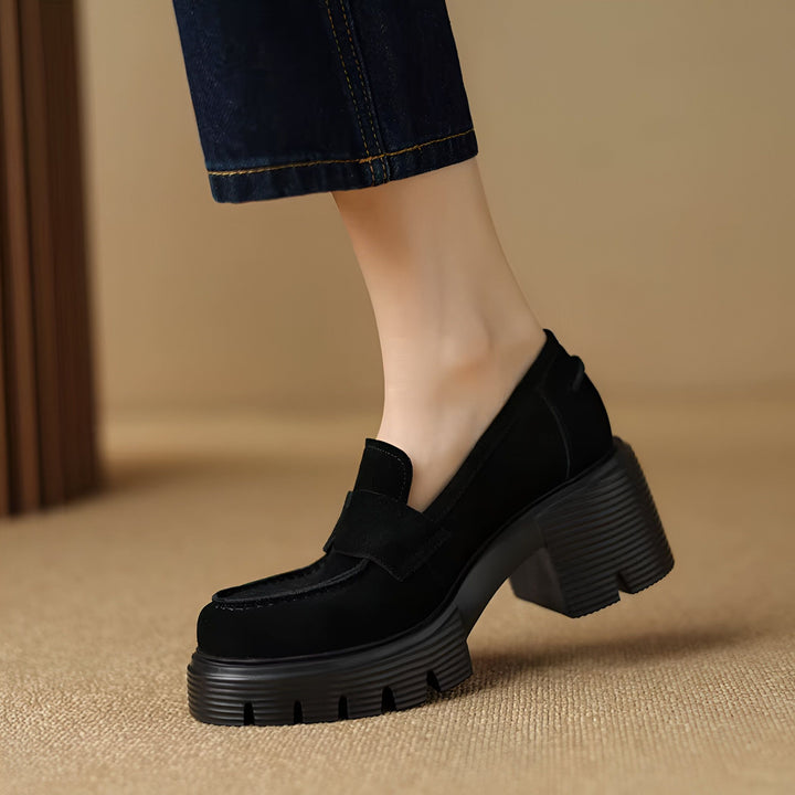Gros plan d'un mocassin noir à talons plateforme sur un pied féminin. La chaussure est portée avec un jean bleu foncé. Mode et style., 45286629769397,45286629802165,45286629834933,45286629867701,45286629900469,45286629933237,45286629966005,45286629998773,45286630031541,45286630064309