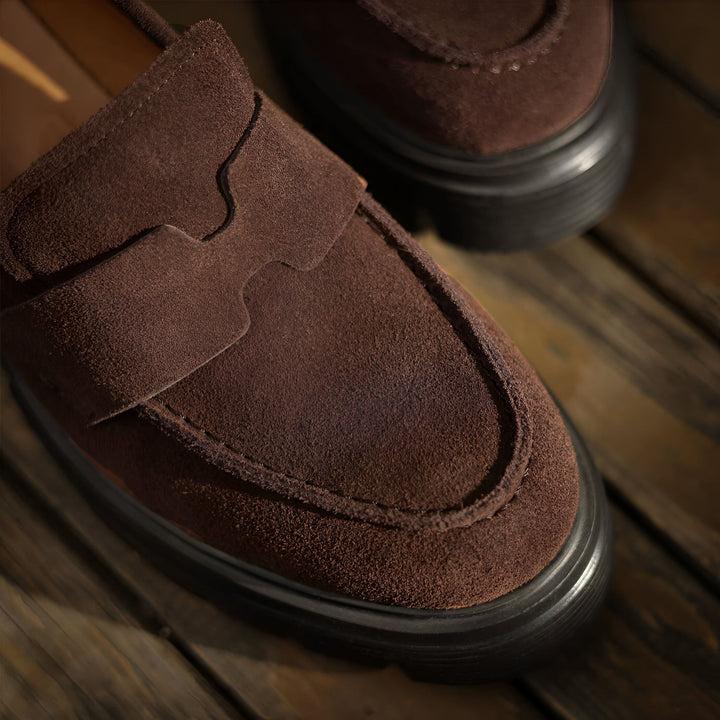 Gros plan sur des mocassins en daim marron à semelle noire épaisse. Chaussures élégantes et confortables pour hommes., 45286629769397,45286629802165,45286629834933,45286629867701,45286629900469,45286629933237,45286629966005,45286629998773,45286630031541,45286630064309