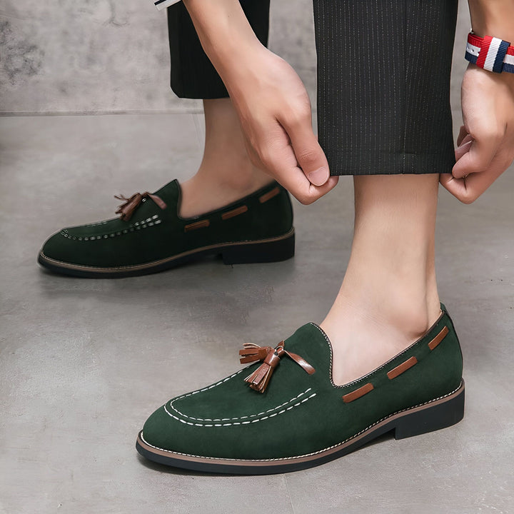 Homme ajustant son pantalon pour montrer des mocassins verts en daim avec des glands en cuir marron et des détails de couture blanche. Chaussures élégantes et décontractées pour hommes., 45287111819445,45287111852213,45287111884981,45287111917749,45287111950517,45287111983285,45287112016053,45287112048821,45287112081589,45287112114357