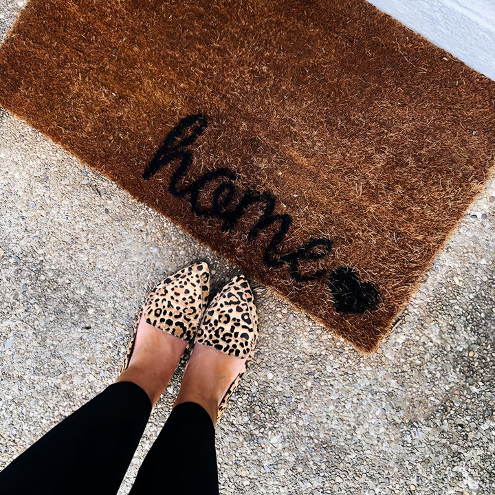 Vue en plongée des pieds d'une femme portant des chaussures à imprimé léopard devant un paillasson en fibre de coco avec le mot "Home" écrit en noir et un petit coeur., 45287154319541,45287154352309,45287154385077,45287154417845,45287154450613,45287154483381,45287154516149,45287154548917,45287154581685,45287154614453,45287154647221,45287154679989