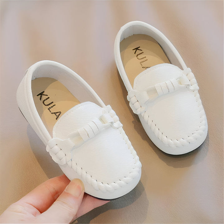 Mocassins blancs pour enfants de la marque KULA, présentés sur fond beige. Une main tient une chaussure, montrant les détails comme la couture décorative et l'ornement sur le dessus., 45287045103797,45287045136565,45287045169333,45287045202101,45287045234869,45287045267637,45287045300405,45287045333173,45287045365941,45287045398709,45287045431477,45287045464245,45287045497013,45287045529781,45287045562549,45287045595317,45287045628085,45287045660853,45287045693621,45287045726389,45287045759157,4528704