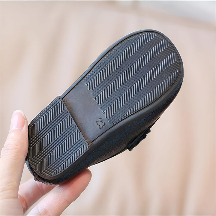 Gros plan d'une main tenant une chaussure noire pour enfant. On voit la semelle antidérapante texturée avec le numéro de pointure "23" gravé. Idéal pour la marche et le confort des petits pieds., 45287045103797,45287045136565,45287045169333,45287045202101,45287045234869,45287045267637,45287045300405,45287045333173,45287045365941,45287045398709,45287045431477,45287045464245,45287045497013,45287045529781,45287045562549,45287045595317,45287045628085,45287045660853,45287045693621,45287045726389,452870457