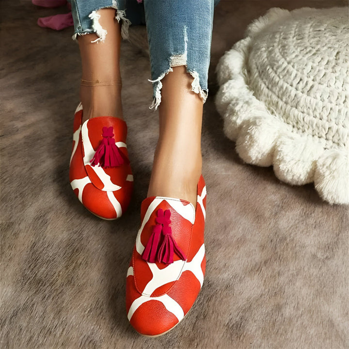 Vue rapprochée de mocassins en cuir orange et blanc à glands portés avec un jean troué sur un tapis texturé. Chaussures de mode uniques et confortables., 45286643171509,45286643204277,45286643237045,45286643269813,45286643302581,45286643335349,45286643368117,45286643400885,45286643433653