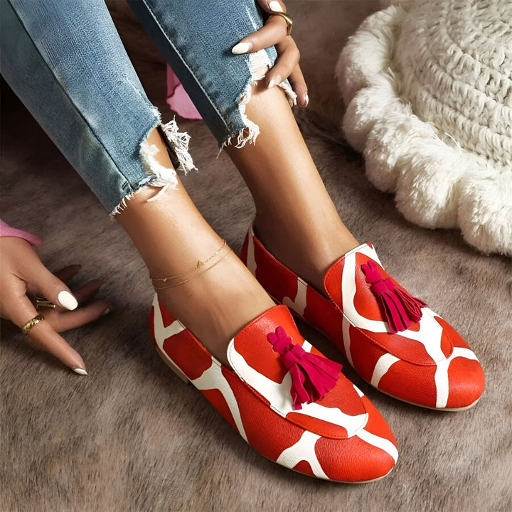 Gros plan sur des mocassins femme rouge vif et blanc avec des glands, portés avec un jean déchiré et une chaîne de cheville dorée. Style décontracté et tendance., 45286643171509,45286643204277,45286643237045,45286643269813,45286643302581,45286643335349,45286643368117,45286643400885,45286643433653