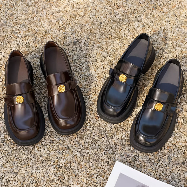 Gros plan de mocassins en cuir marron et noir avec détails dorés sur un fond de gravier. Chaussures élégantes et modernes, idéales pour toutes les occasions., 45286630490293,45286630523061,45286630555829,45286630588597,45286630621365,45286630654133,45286630686901,45286630719669,45286630752437,45286630785205