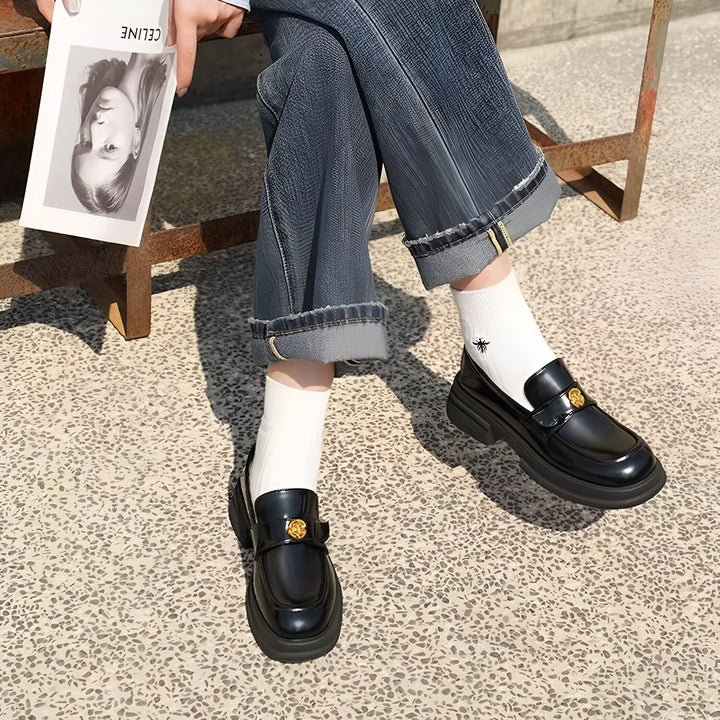 Gros plan sur une personne portant des mocassins noirs brillants avec des chaussettes blanches, un jean bleu et tenant un magazine "Céline". Le style est décontracté et tendance., 45286630490293,45286630523061,45286630555829,45286630588597,45286630621365,45286630654133,45286630686901,45286630719669,45286630752437,45286630785205
