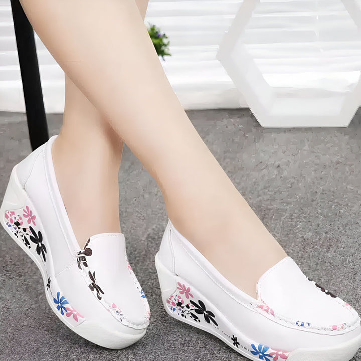 Gros plan sur des pieds portant des mocassins compensés blancs avec des motifs floraux colorés. Chaussures confortables et élégantes, parfaites pour le printemps et l'été. Mode décontractée et féminine., 45286966722741,45286966755509,45286966788277,45286966821045,45286966853813,45286966886581,45286966919349,45286966952117,45286966984885,45286967017653,45286967050421,45286967083189,45286967115957,45286967148725,45286967181493,45286967214261