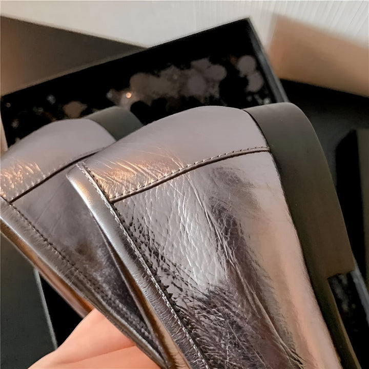 Gros plan sur des chaussures en cuir argenté, reflétant la lumière. Détail de couture et talon noir visible. Boîte d'emballage partiellement visible en arrière-plan., 45286733185205,45286733217973,45286733250741,45286733283509,45286733316277,45286733349045,45286733381813