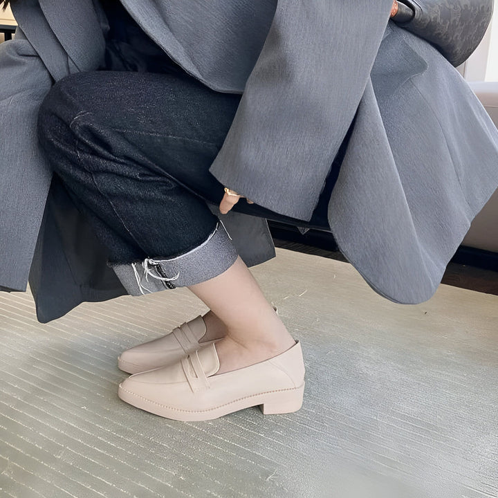 Gros plan sur une personne accroupie portant un blazer gris, un jean noir retroussé et des mocassins beiges à talons. Style décontracté et élégant., 45286732693685,45286732726453,45286732759221,45286732791989,45286732824757,45286732857525,45286732890293,45286732923061,45286732955829,45286732988597,45286733021365,45286733054133,45286733086901,45286733119669