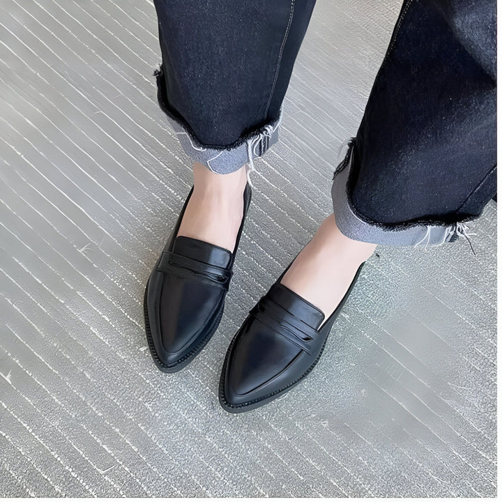 Gros plan sur des mocassins pointus noirs en cuir portés avec un jean foncé retroussé sur un tapis gris. Chaussures élégantes, look décontracté et moderne., 45286732693685,45286732726453,45286732759221,45286732791989,45286732824757,45286732857525,45286732890293,45286732923061,45286732955829,45286732988597,45286733021365,45286733054133,45286733086901,45286733119669