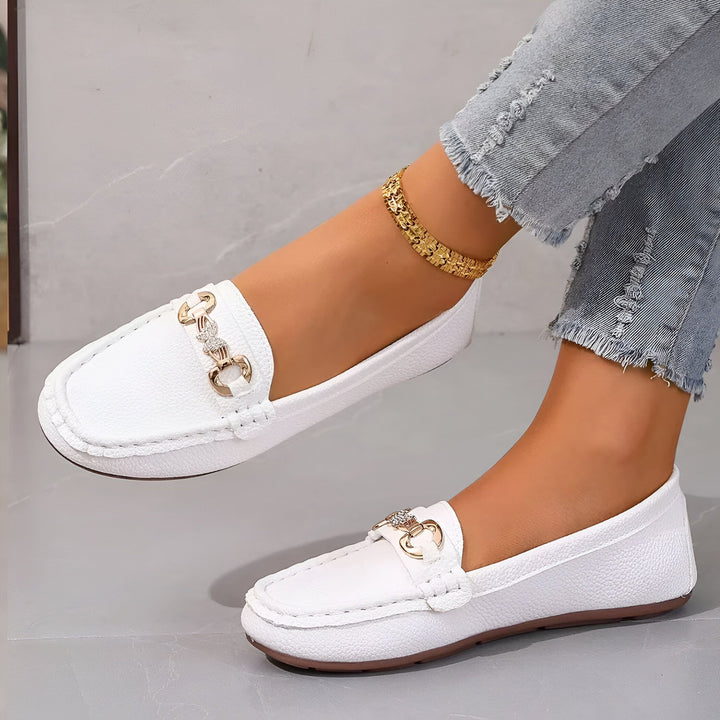 Gros plan de mocassins blancs pour femmes avec des boucles dorées, portés avec un jean décontracté et une chaîne de cheville dorée. Chaussures élégantes et confortables., 45286627999925,45286628032693,45286628065461,45286628098229,45286628130997,45286628163765,45286628196533,45286628229301,45286628262069,45286628294837,45286628327605,45286628360373,45286628393141,45286628425909,45286628458677,45286628491445,45286628524213,45286628556981,45286628589749,45286628622517,45286628655285,45286628688053,4