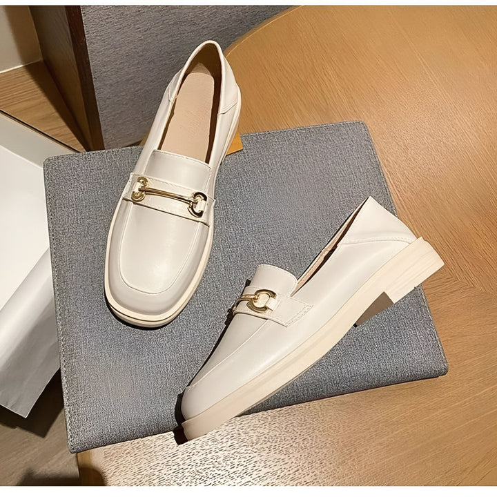 Deux mocassins en cuir blanc cassé avec un ornement doré, posés sur un coussin gris, sur une table en bois. Chaussures élégantes et confortables., 45286721323189,45286721355957,45286721388725,45286721421493,45286721454261,45286721487029,45286721519797,45286721552565,45286721585333,45286721618101,45286721650869,45286721683637,45286721716405,45286721749173,45286721781941,45286721814709,45286721847477,45286721880245,45286721913013,45286721945781,45286721978549,45286722011317,45286722044085,4528672207685