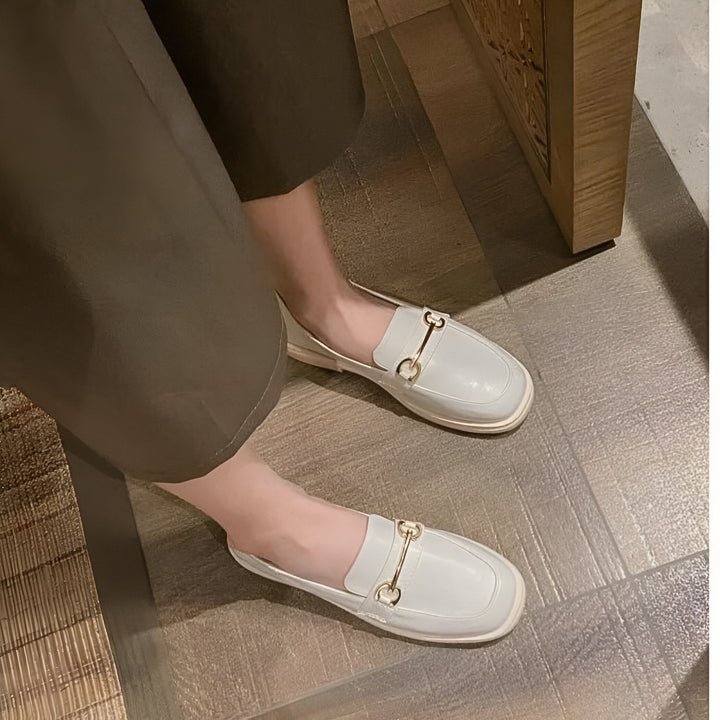 Vue rapprochée d'une personne portant des mocassins blancs en cuir avec un détail doré. Chaussures plates élégantes, idéales pour un look chic et décontracté. Jambes vêtues d'un pantalon., 45286721323189,45286721355957,45286721388725,45286721421493,45286721454261,45286721487029,45286721519797,45286721552565,45286721585333,45286721618101,45286721650869,45286721683637,45286721716405,45286721749173,45286721781941,45286721814709,45286721847477,45286721880245,45286721913013,45286721945781,452867219785