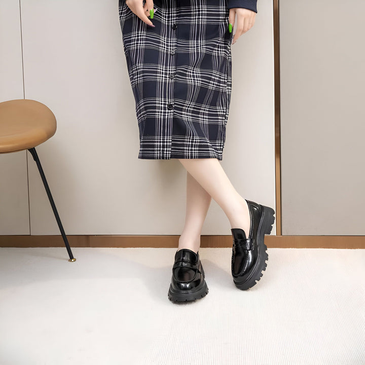 Une femme portant une jupe à carreaux et des chaussures vernies noires à semelles épaisses. Vue rapprochée des chaussures et des jambes croisées., 45286915899573,45286915932341,45286915965109,45286915997877,45286916030645,45286916063413,45286916096181,45286916128949,45286916161717,45286916194485,45286916227253,45286916260021,45286916292789,45286916325557,45286916358325,45286916391093