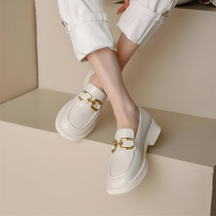 Vue rapprochée des pieds d'une personne portant des mocassins blancs en cuir avec des ornements dorés sur des marches claires. Chaussures élégantes et confortables., 45286735446197,45286735478965,45286735511733,45286735544501,45286735577269,45286735610037,45286735642805,45286735675573,45286735708341,45286735741109,45286735773877,45286735806645,45286735839413,45286735872181