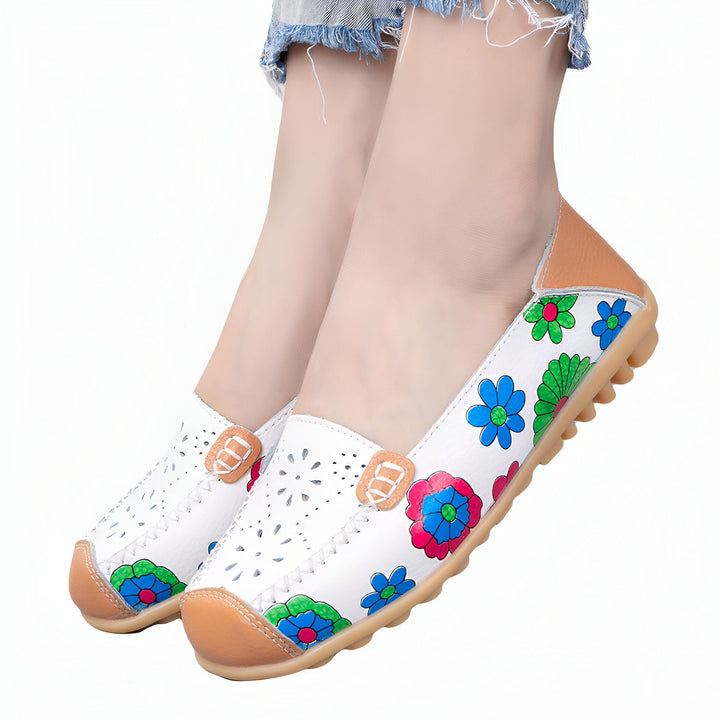 Chaussures plates blanches en cuir avec motifs floraux colorés, portées par une personne. Détails perforés et semelle en caoutchouc. Idéales pour un look décontracté et confortable., 45286857539765,45286857572533,45286857605301,45286857638069,45286857670837,45286857703605,45286857736373,45286857769141,45286857801909,45286857834677,45286857867445,45286857900213,45286857932981,45286857965749,45286857998517,45286858031285,45286858064053,45286858096821,45286858129589,45286858162357,45286858195125,45286