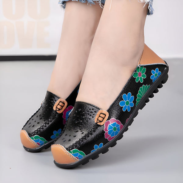 Gros plan sur des chaussures plates noires en cuir avec des motifs floraux colorés portées par une femme. Les chaussures ont des détails perforés et un ornement décoratif sur le dessus., 45286857539765,45286857572533,45286857605301,45286857638069,45286857670837,45286857703605,45286857736373,45286857769141,45286857801909,45286857834677,45286857867445,45286857900213,45286857932981,45286857965749,45286857998517,45286858031285,45286858064053,45286858096821,45286858129589,45286858162357,45286858195125,452