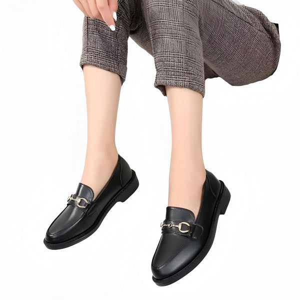 Une femme assise porte des mocassins noirs en cuir avec des ornements dorés. Chaussures élégantes portées avec un pantalon à carreaux. Mode et style., 45286727844021,45286727876789,45286727909557,45286727942325,45286727975093,45286728007861,45286728040629,45286728073397,45286728106165