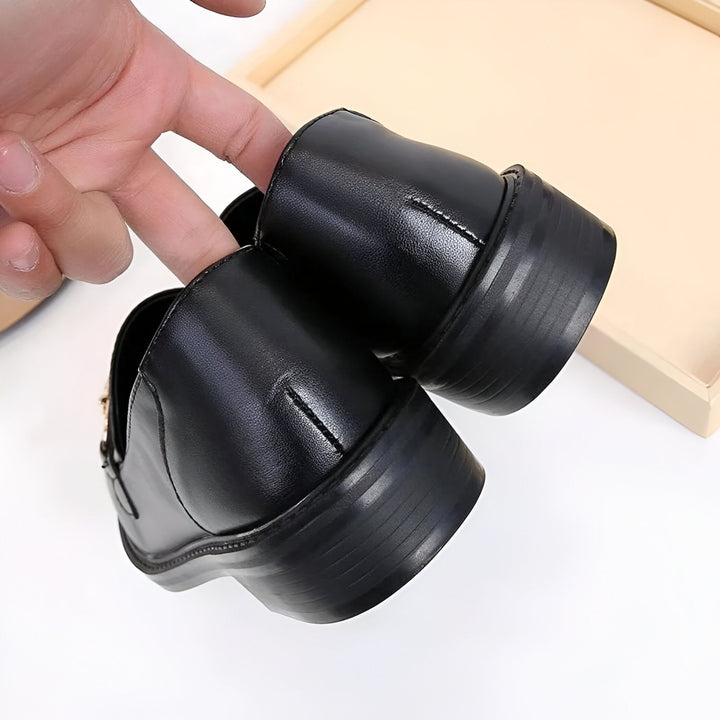 Gros plan de chaussures noires en cuir, une main les manipule délicatement. On aperçoit le talon bloc et le design élégant des mocassins. Mode, style, chaussures en cuir, accessoires., 45286727844021,45286727876789,45286727909557,45286727942325,45286727975093,45286728007861,45286728040629,45286728073397,45286728106165