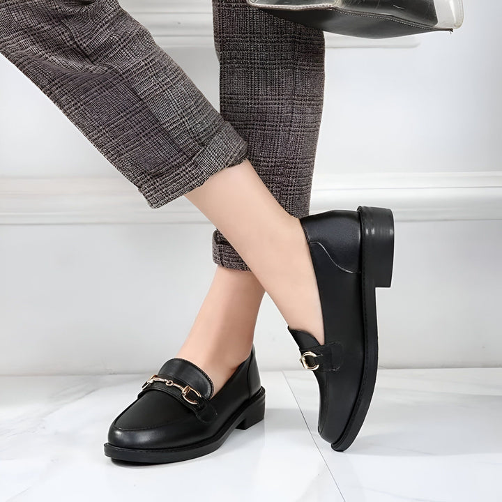 Gros plan de mocassins noirs en cuir portés avec un pantalon à carreaux gris. Détail boucle dorée sur la chaussure. Style élégant et décontracté., 45286727844021,45286727876789,45286727909557,45286727942325,45286727975093,45286728007861,45286728040629,45286728073397,45286728106165