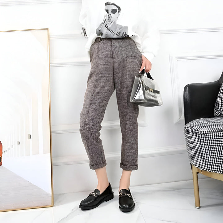 Femme portant un pantalon à carreaux marron, un pull blanc imprimé, des mocassins noirs et tenant un sac à main transparent. Style décontracté et élégant., 45286727844021,45286727876789,45286727909557,45286727942325,45286727975093,45286728007861,45286728040629,45286728073397,45286728106165