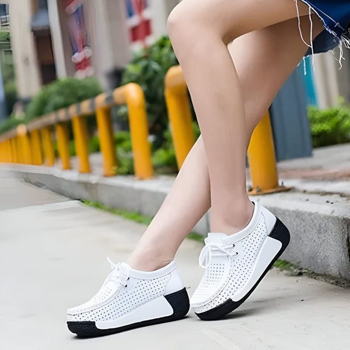 Gros plan sur des chaussures blanches à lacets avec une semelle compensée noire, portées par une femme assise sur un muret en béton. L'arrière-plan est flou avec des éléments urbains., 45286652477621,45286652510389,45286652543157,45286652575925,45286652608693,45286652641461,45286652674229,45286652706997,45286652739765,45286652772533,45286652805301,45286652838069,45286652870837,45286652903605,45286652936373,45286652969141,45286653001909,45286653034677,45286653067445,45286653100213,45286653132981,452