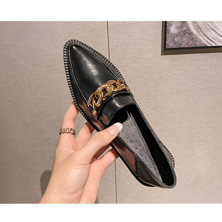 Mocassin noir en cuir verni avec chaîne dorée, tenu par une main féminine. Chaussure élégante et tendance, idéale pour un look chic et décontracté. Accessoire de mode parfait pour compléter une tenue., 45286940147893,45286940180661,45286940213429,45286940246197,45286940278965,45286940311733,45286940344501,45286940377269,45286940410037