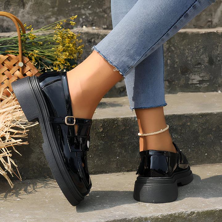 Gros plan d'une femme assise sur des marches en jean avec des mocassins noirs vernis à plateforme et une chevillère. Panier avec fleurs en arrière-plan. Chaussures tendance, style décontracté., 45286866419893,45286866452661,45286866485429,45286866518197,45286866550965,45286866583733