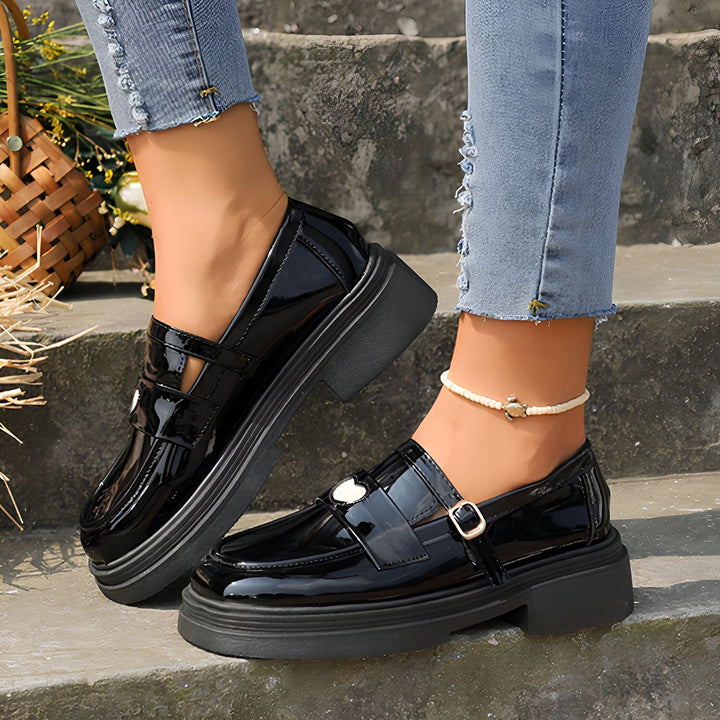 Gros plan de chaussures mocassins noires vernies à semelles compensées portées avec un jean et une cheville ornée d'une chaîne., 45286866419893,45286866452661,45286866485429,45286866518197,45286866550965,45286866583733