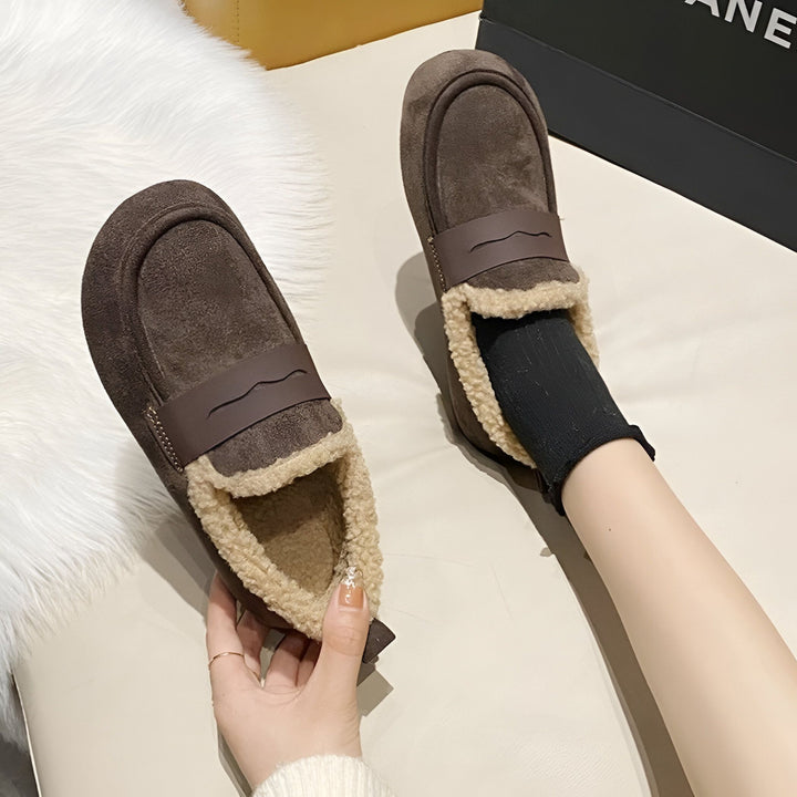 Vue rapprochée de mocassins marron en daim avec bordure en fausse fourrure beige. Une main tient une chaussure tandis qu'un pied porte une chaussette noire et l'autre mocassin., 45286657556661,45286657589429,45286657622197,45286657654965,45286657687733,45286657720501,45286657753269,45286657786037,45286657818805,45286657851573,45286657884341,45286657917109,45286657949877,45286657982645,45286658015413,45286658048181,45286658080949,45286658113717,45286658146485,45286658179253,45286658212021