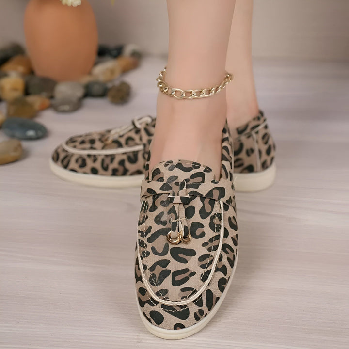 Gros plan de chaussures plates à motif léopard portées, avec une chaîne de cheville dorée., 45286648250549,45286648283317,45286648316085,45286648348853,45286648381621,45286648414389,45286648447157,45286648479925