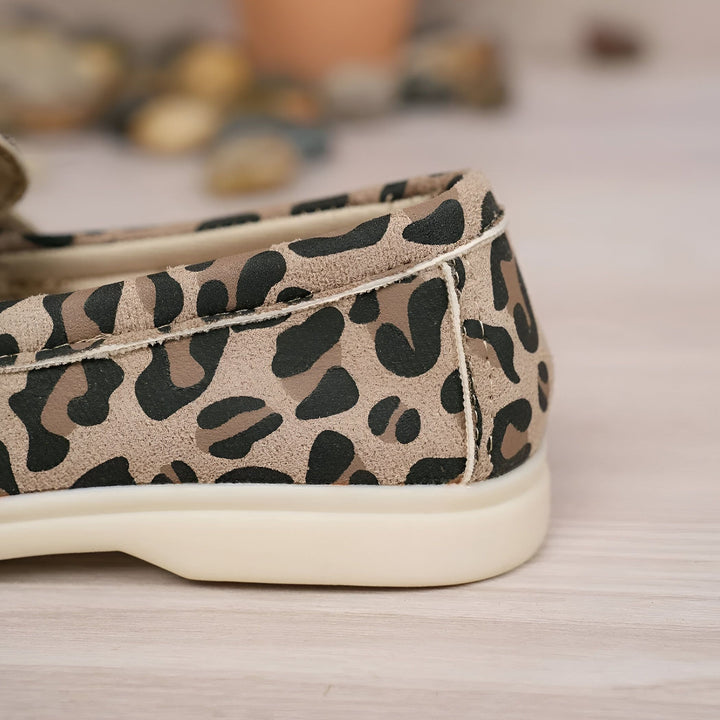 Gros plan d'une chaussure plate à imprimé léopard avec une semelle blanche épaisse. La chaussure est sur une surface en bois clair., 45286648250549,45286648283317,45286648316085,45286648348853,45286648381621,45286648414389,45286648447157,45286648479925