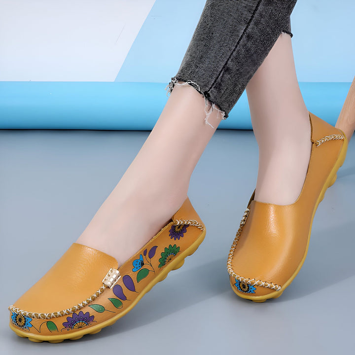 Gros plan de mocassins en cuir jaune moutarde ornés de motifs floraux colorés, portés avec un jean gris. Chaussures décontractées et confortables pour femme. Style élégant et artisanal., 45286851346613,45286851379381,45286851412149,45286851444917,45286851477685,45286851510453,45286851543221,45286851575989,45286851608757,45286851641525,45286851674293,45286851707061,45286851739829,45286851772597,45286851805365,45286851838133,45286851870901,45286851903669,45286851936437,45286851969205,45286852001973,4