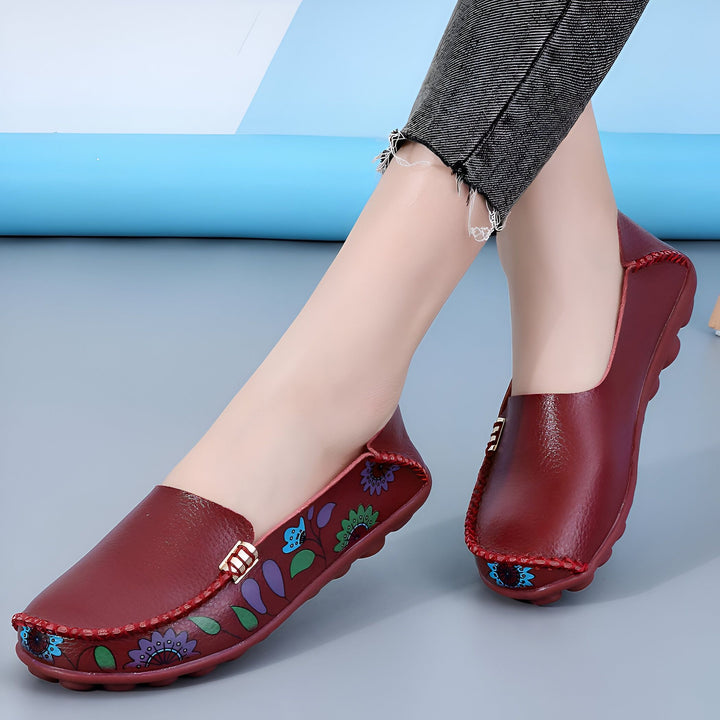 Gros plan de mocassins bordeaux en cuir portés par une femme. Les chaussures sont décorées de motifs floraux colorés et d'une boucle dorée., 45286851346613,45286851379381,45286851412149,45286851444917,45286851477685,45286851510453,45286851543221,45286851575989,45286851608757,45286851641525,45286851674293,45286851707061,45286851739829,45286851772597,45286851805365,45286851838133,45286851870901,45286851903669,45286851936437,45286851969205,45286852001973,45286852034741,45286852067509,45286852100277,4528