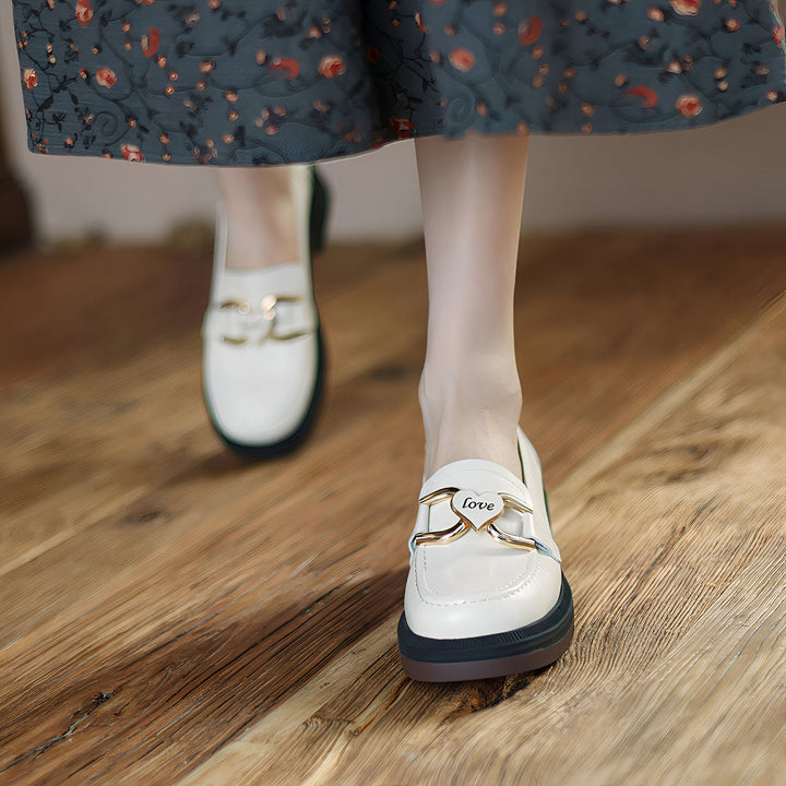 Gros plan sur des mocassins blancs avec détail doré en forme de cœur portant le mot "Love". Portés avec une jupe à motif floral sur un plancher en bois. Chaussures élégantes et confortables., 45286908756149,45286908788917,45286908821685,45286908854453,45286908887221,45286908919989,45286908952757,45286908985525,45286909018293,45286909051061,45286909083829,45286909116597,45286909149365,45286909182133