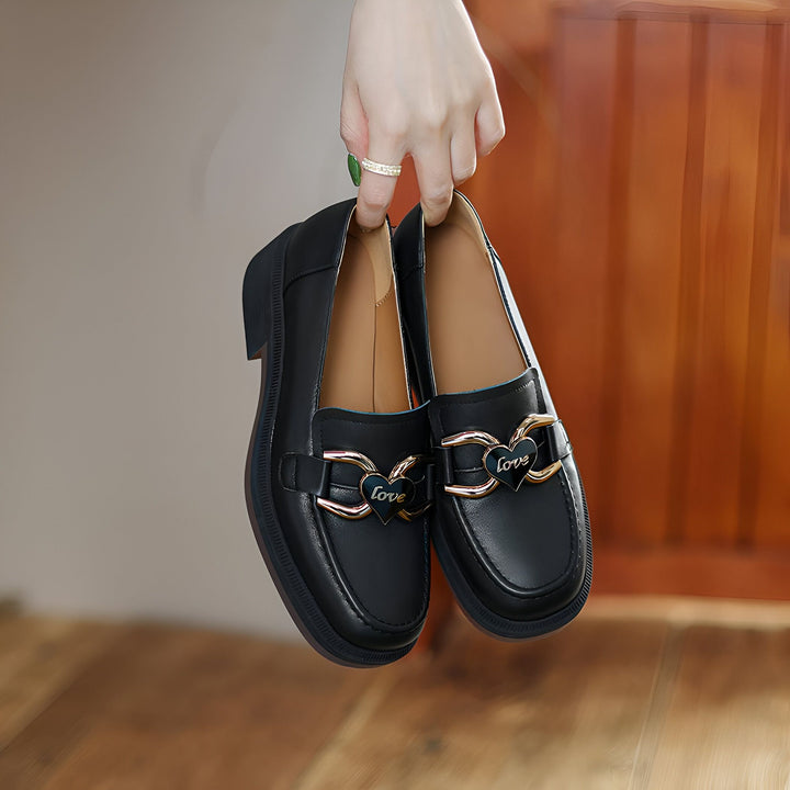 Une main tenant une paire d'élégants mocassins noirs en cuir. Les chaussures sont ornées de boucles dorées en forme de cœur avec le mot "Love". Parfaites pour un look chic et confortable., 45286908756149,45286908788917,45286908821685,45286908854453,45286908887221,45286908919989,45286908952757,45286908985525,45286909018293,45286909051061,45286909083829,45286909116597,45286909149365,45286909182133